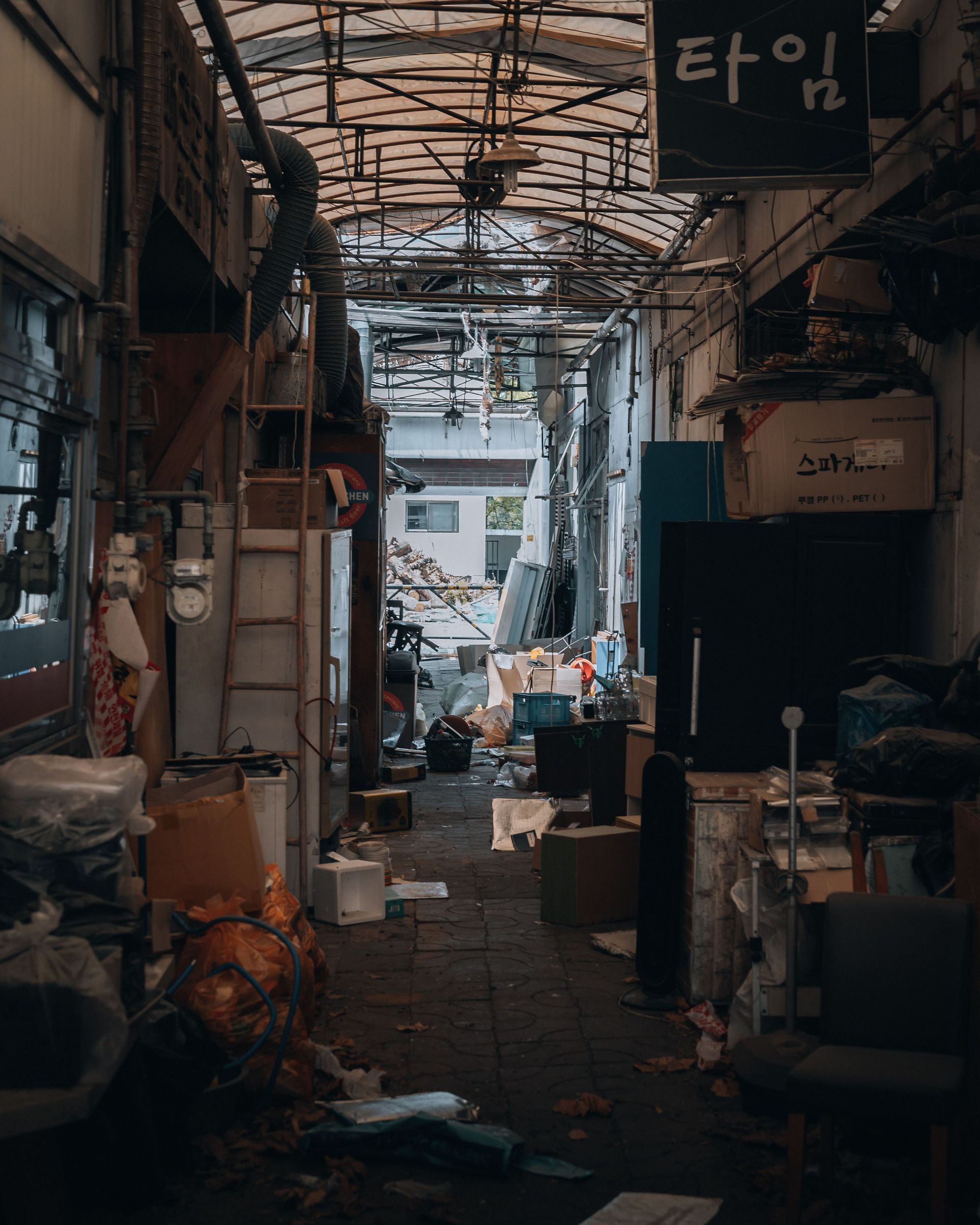A narrow cluttered alley in Seoul, South Korea, revealing a messy urban market scene.